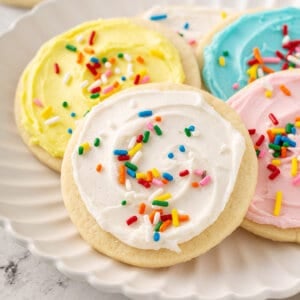 cookie with white sugar cookie frosting and sprinkles on plate