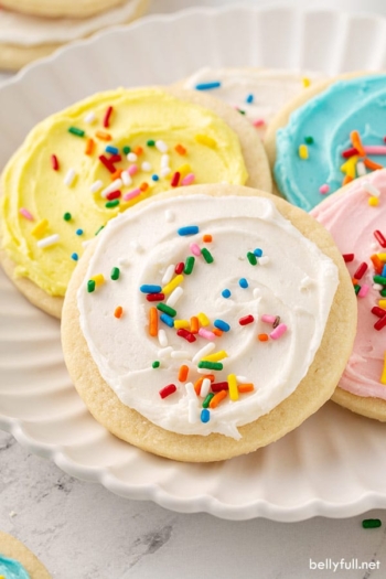 cookie with white sugar cookie frosting and sprinkles on plate