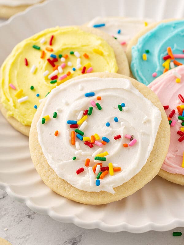 cookie with white sugar cookie frosting and sprinkles on plate