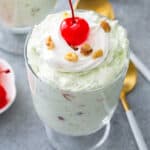 Watergate Salad in glass cup with whipped cream and a Maraschino cherry