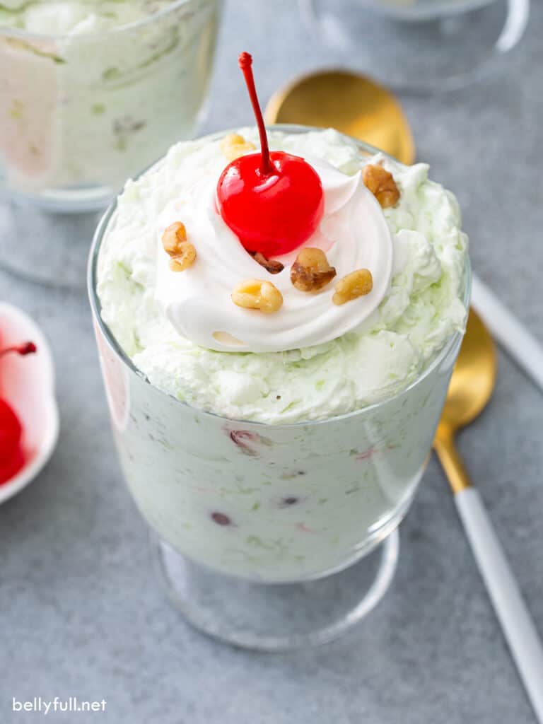 Watergate Salad in glass cup with whipped cream and a Maraschino cherry