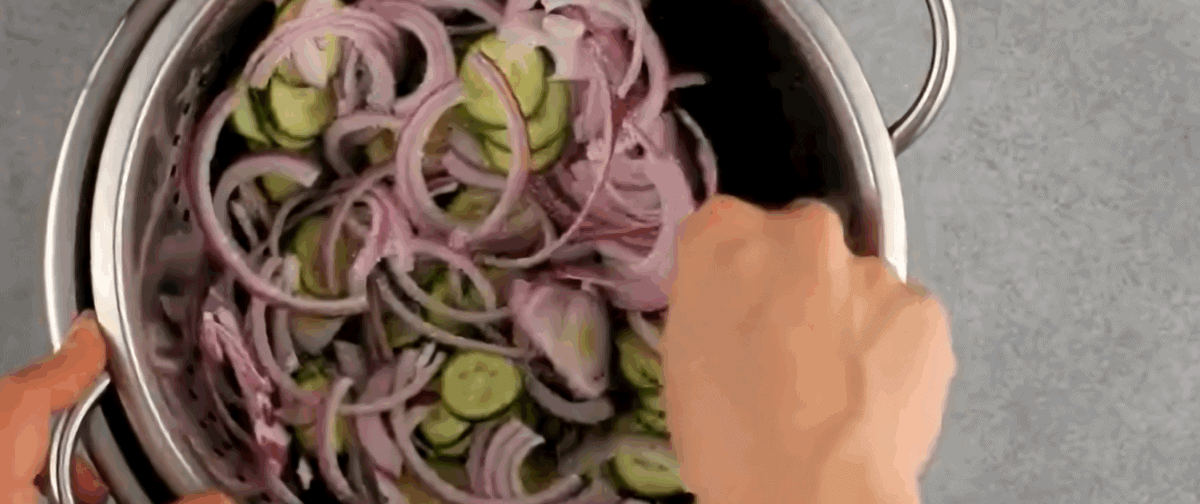 Cucumbers and onions in a colander.