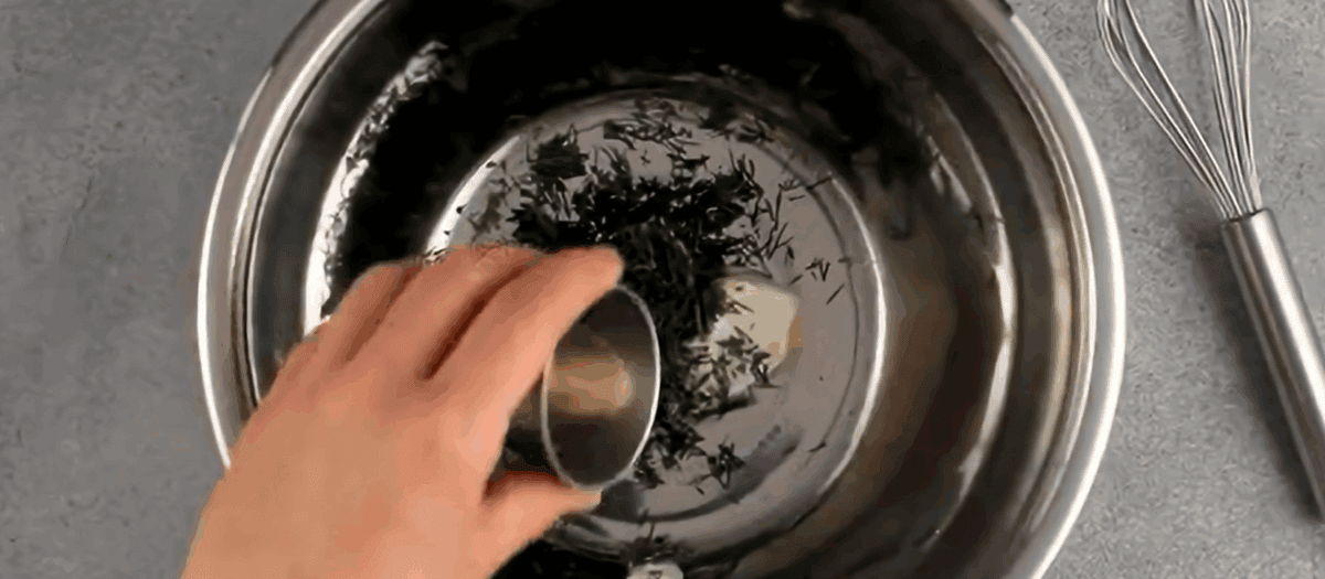 Combining the ingredients for the dressing in a stainless steel bowl.