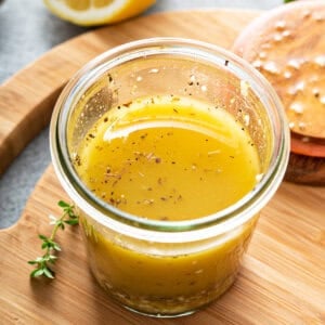 Greek Salad Dressing in glass jar sitting on cutting board