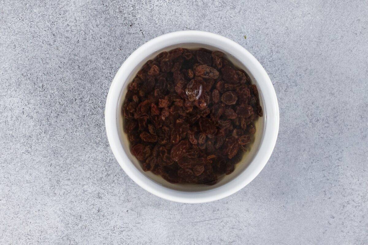 Raisins soaking in a white bowl.