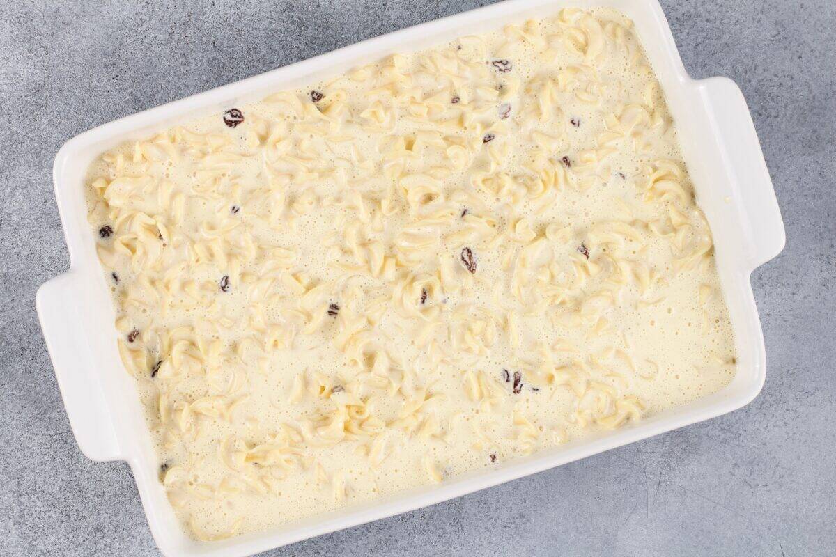 Uncooked noodle kugel in a white baking dish.