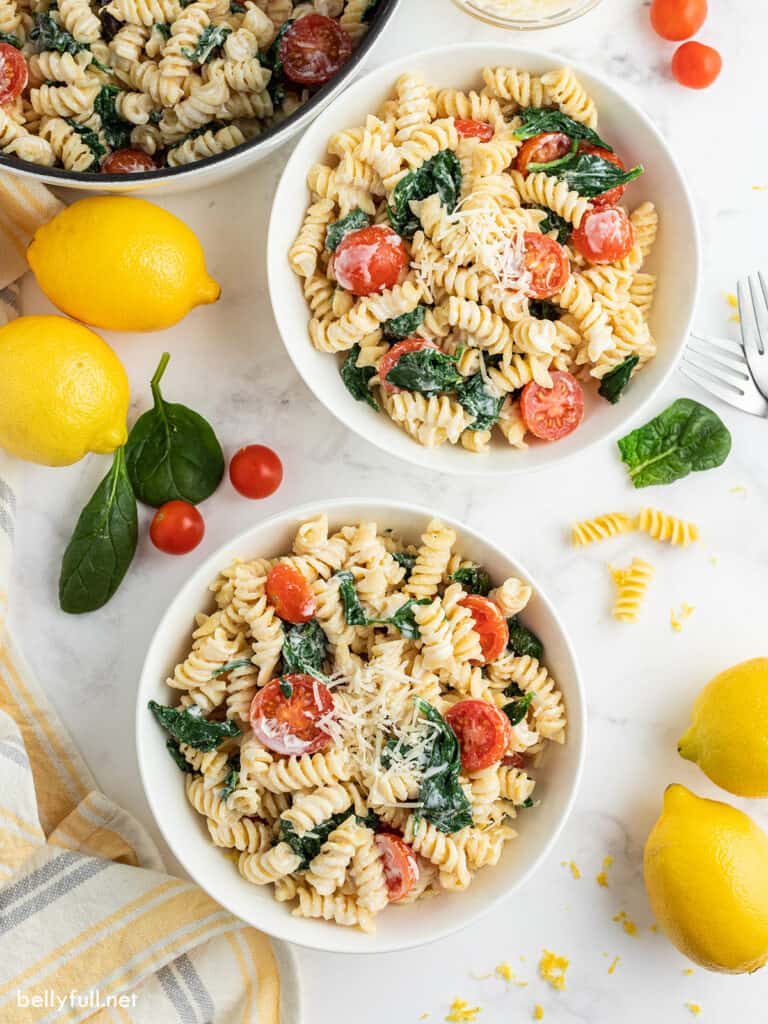 lemon pasta with tomatoes and spinach in 2 white serving bowls