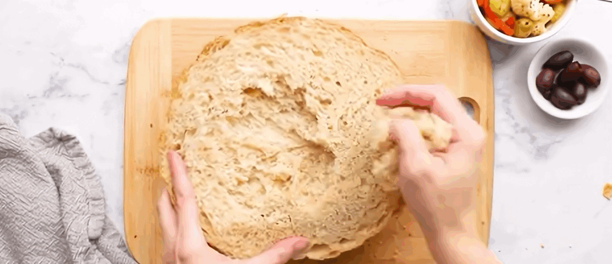 Italian bread cut in half, and hands removing some of the bread so the filling will fit.