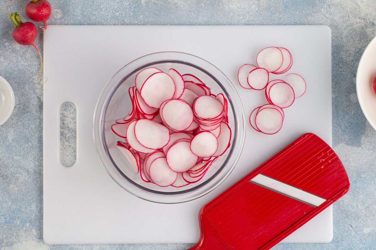 Using a mandolin to slice radishes.