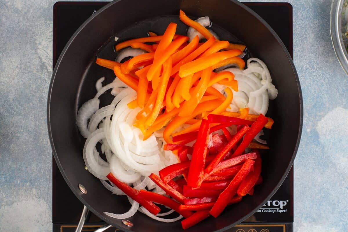 Cooking peppers and onions in a skillet. 