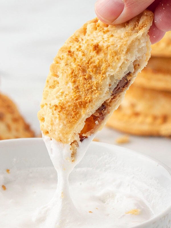 smores hand pie being dip into marshmallow cream