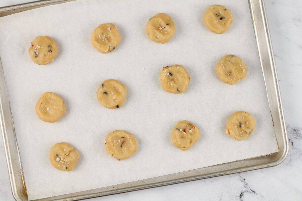 Kitchen sink cookie dough balls on a lined baking sheet.