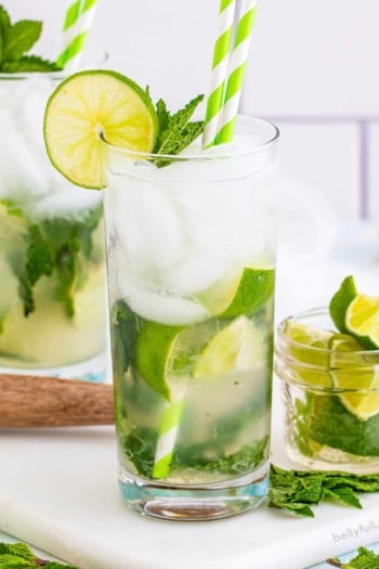 A classic mojito with a small glass of lime wedges to the side