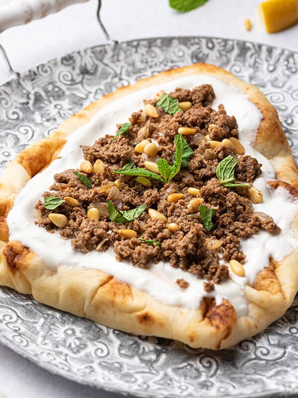 turkey keema on top of yogurt naan bread on ornate plate