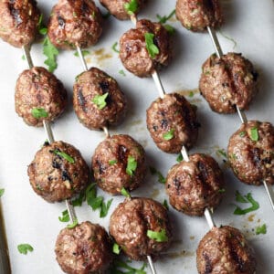 overhead view of beef kofta kebob meatballs on metal skewers