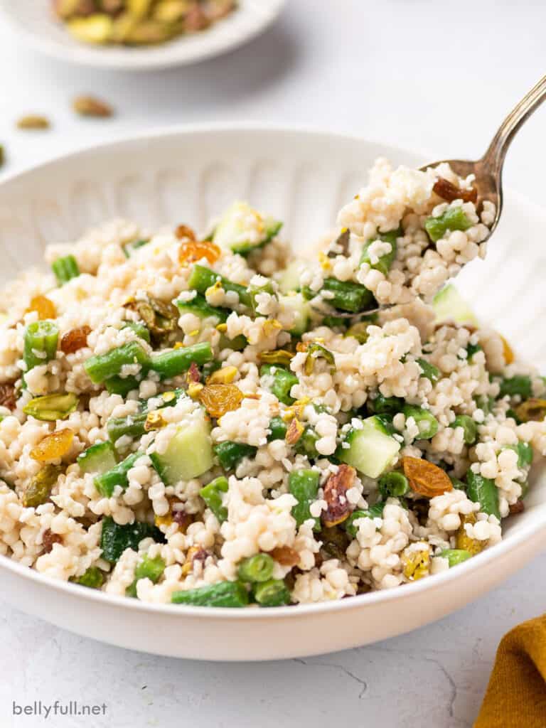 couscous salad in white bowl with spoonful