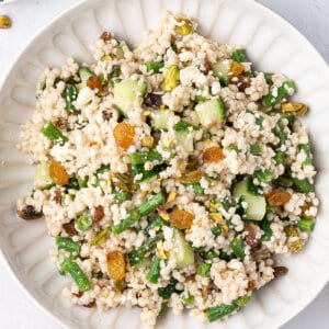 overhead Israeli Couscous Salad with golden raisins and green beans on white plate