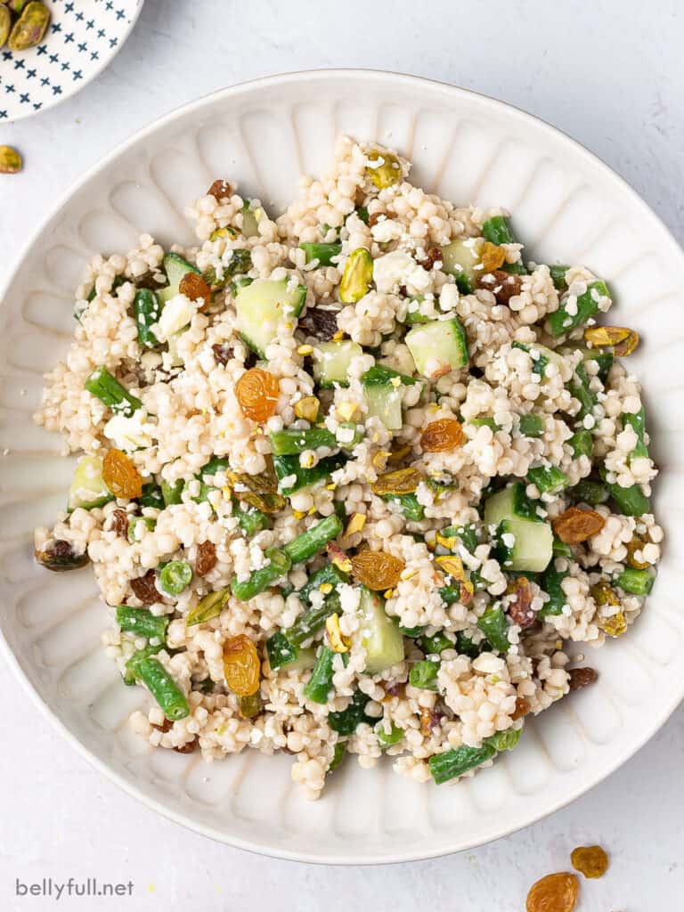 overhead Israeli Couscous Salad with golden raisins and green beans on white plate