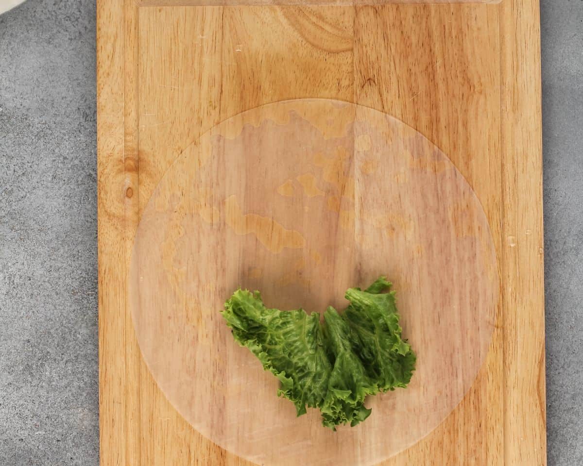 Lettuce on the rice paper on a wooden cutting board.