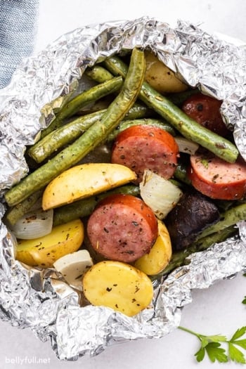 close up cooked kielbasa and vegetable foil packet meal