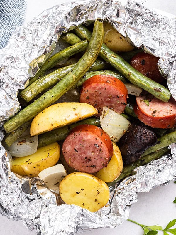 close up cooked kielbasa and vegetable foil packet meal