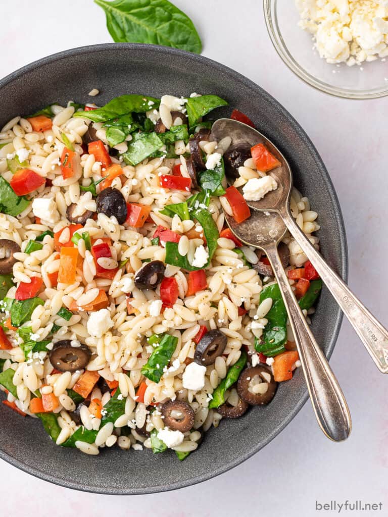 overhead bowl of Mediterranean Orzo Salad with serving spoons