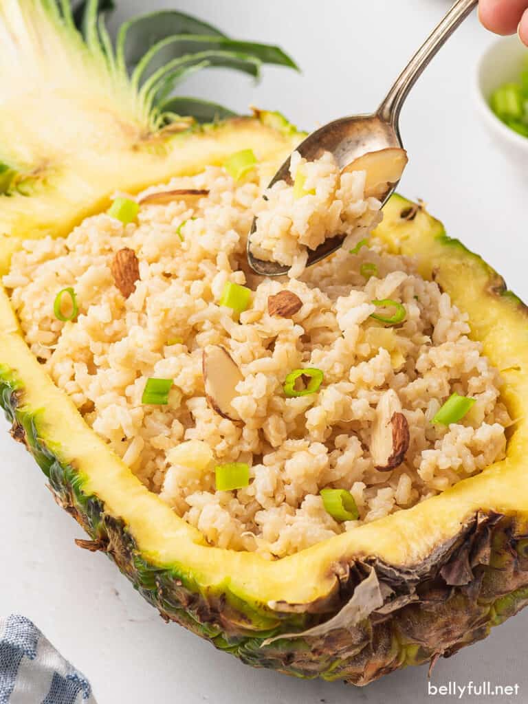 coconut rice piled inside fresh hollowed out pineapple half with spoon