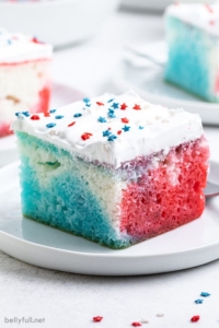 A slice of red white blue poke cake on a white plate