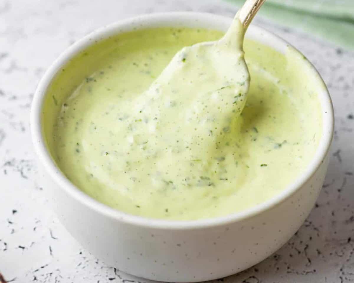 Creamy cilantro sauce for the tacos in a bowl with a spoon.
