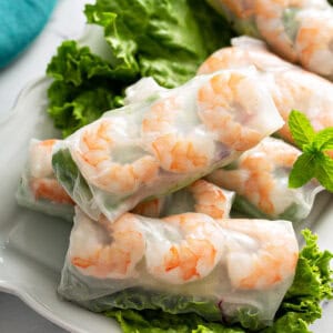 close up fresh shrimp spring rolls on lettuce lined white plate