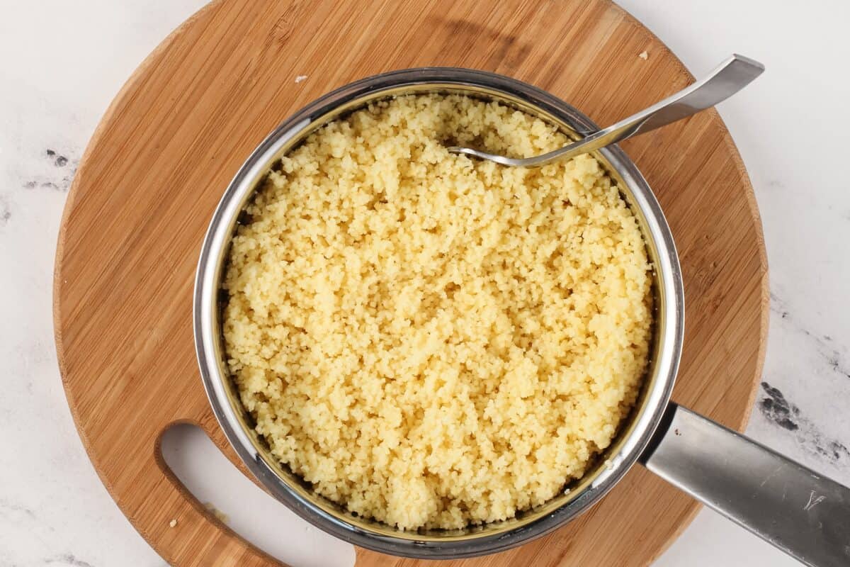Cooked couscous in a pot with a spoon.