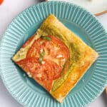 blue plate with square slice of tomato puff pastry tart