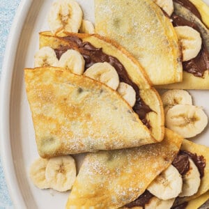 close up overhead 3 banana nutella crepes on white plate