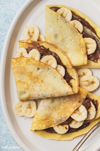 close up overhead 3 banana nutella crepes on white plate