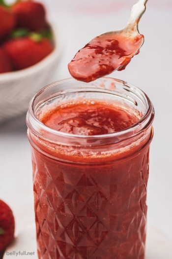 strawberry sauce on spoon over glass jar