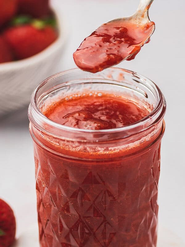 strawberry sauce on spoon over glass jar