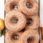 Baked apple cider donuts dipped in cinnamon sugar on a wire rack