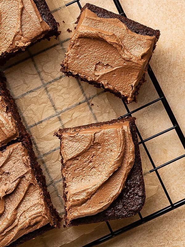 overhead sliced squares of frosted chocolate cake on wire rack