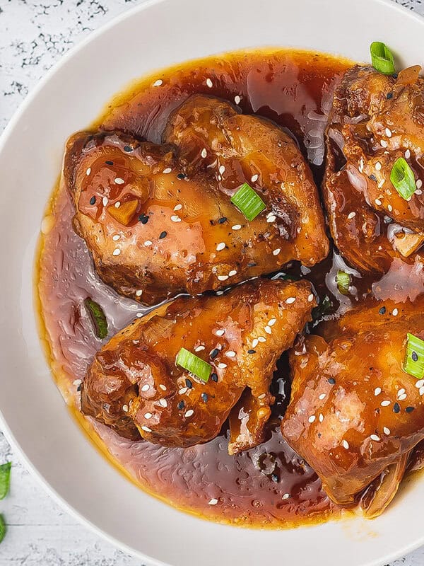 overhead honey garlic chicken thighs coated in sauce on white plate
