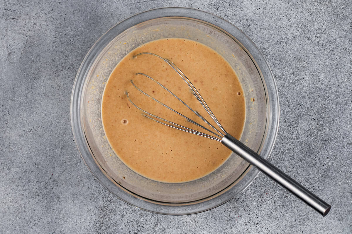 Thai coconut chicken sauce in a glass bowl with a whisk.