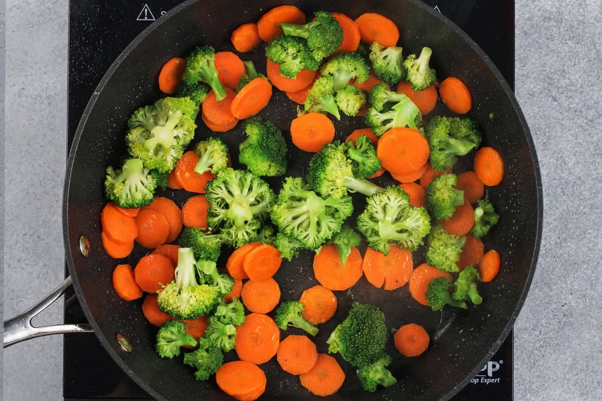 Cooking carrots and broccoli in a skillet.