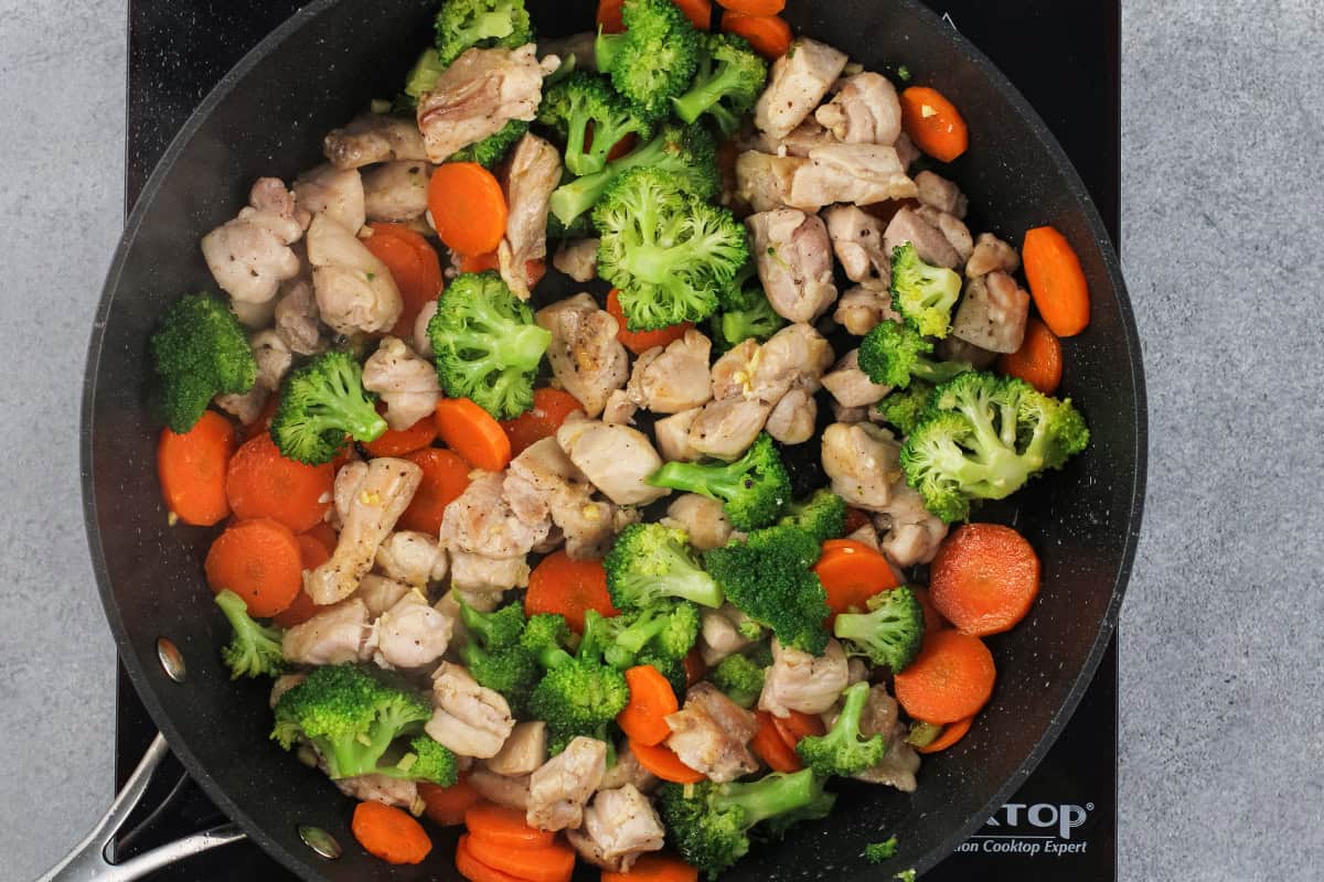 Chicken and veggies cooking in a skillet.