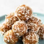 carrot cake energy balls coated in coconut flakes piled on a plate