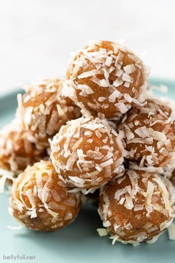 carrot cake energy balls coated in coconut flakes piled on a plate