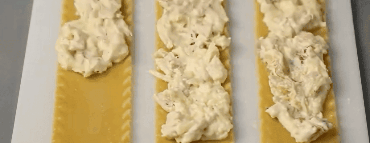 Spreading the chicken filling over the lasagna noodles. 