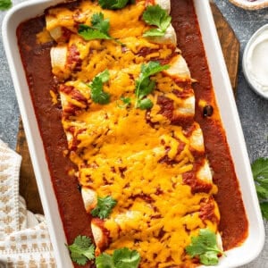 chicken enchiladas covered in melted cheddar cheese in baking dish