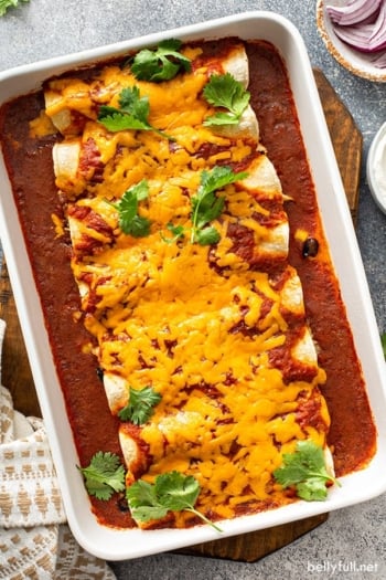 chicken enchiladas covered in melted cheddar cheese in baking dish