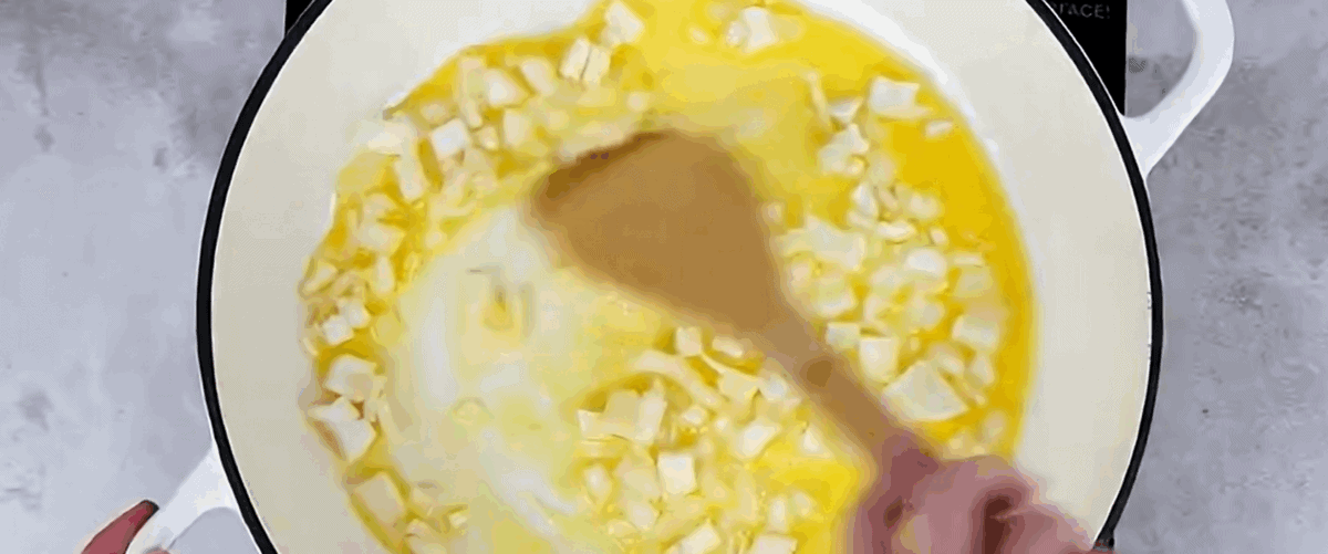 Cooking onions in butter in a white pot.