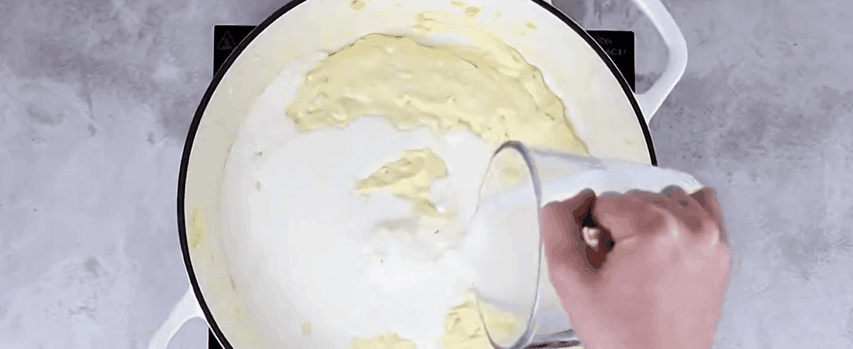Adding cream to the pot of onions and cream cheese.