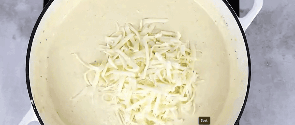 Adding grated cheese to the pot.